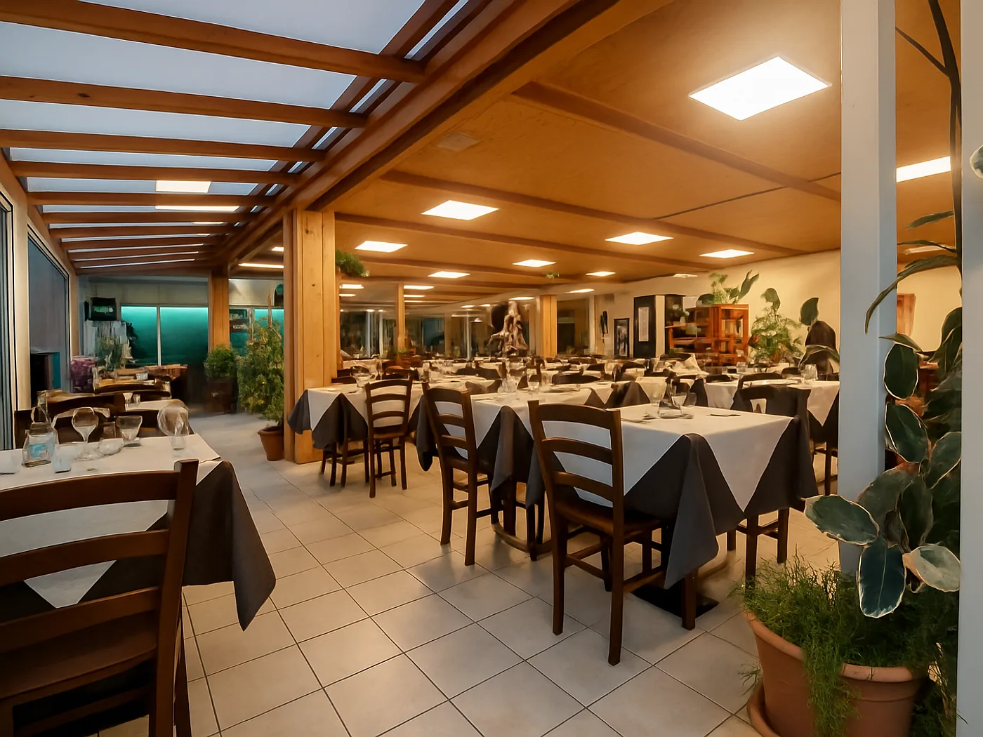 La veranda interna della Trattoria da Corrado, con piante e tavoli apparecchiati